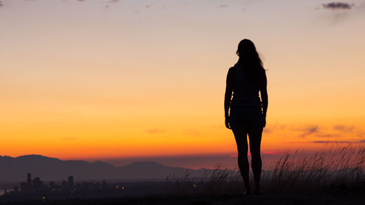 silhouette of a woman watching a sunset or sunrise
